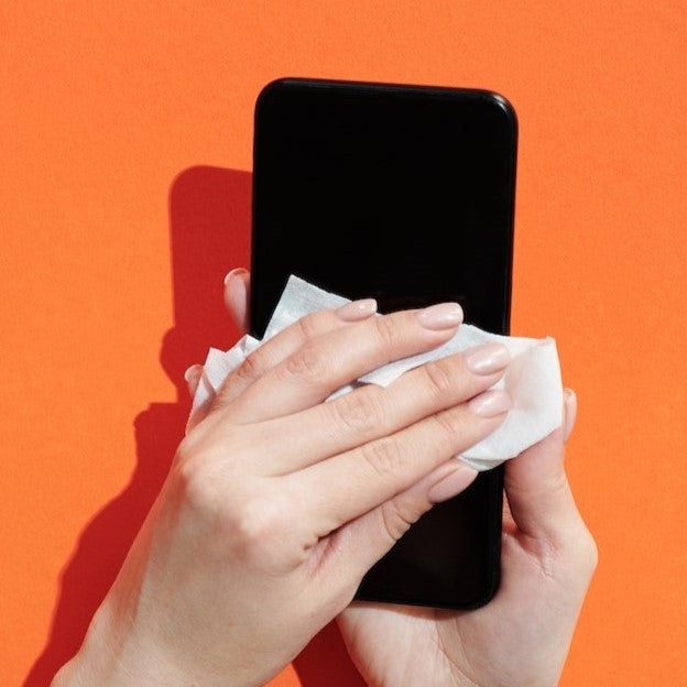 Smartphone wird manuell mit Mikrofasertuch gereinigt – Pflege und Reinigung für streifenfreie Displays.