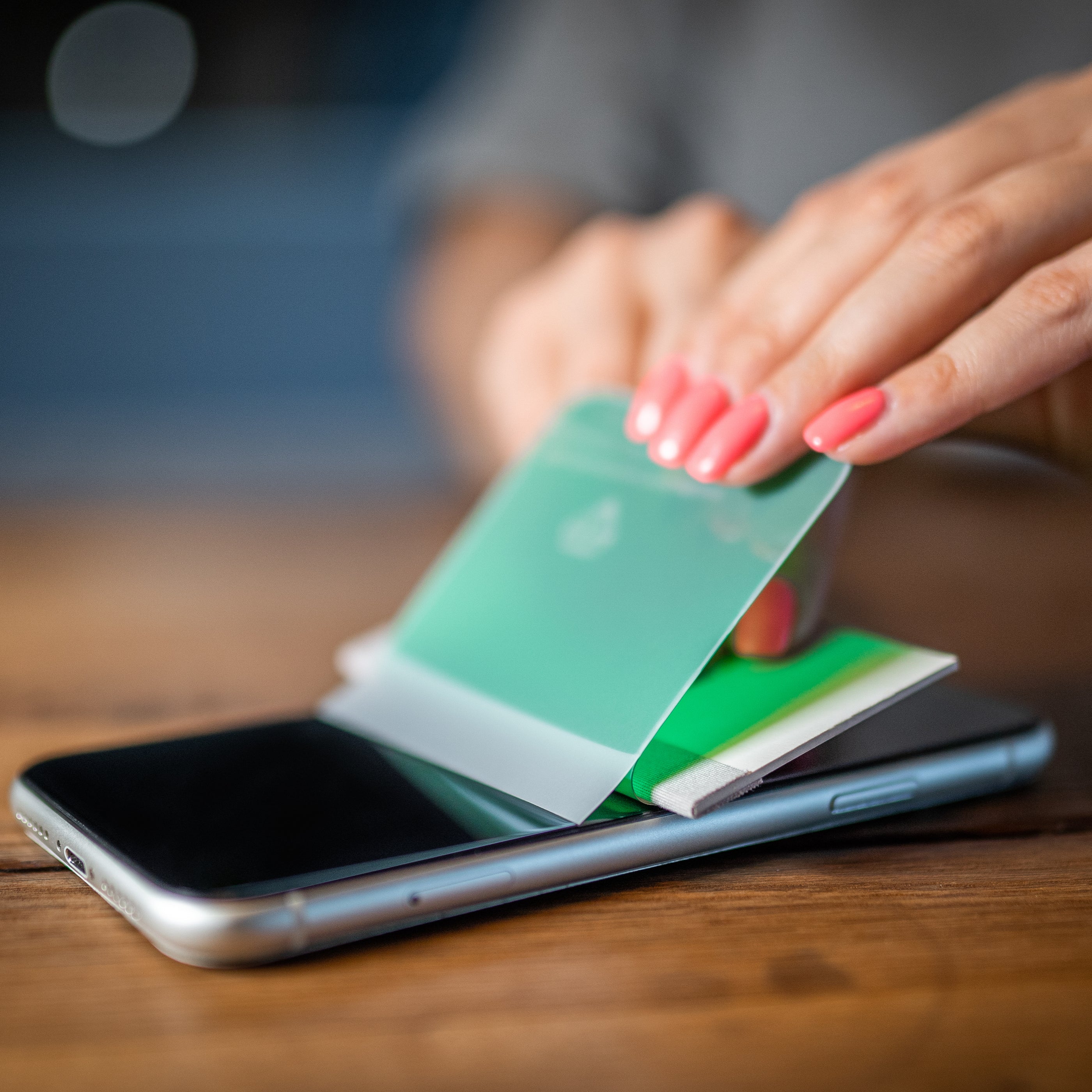 weibliche Hände bringen eine GREENMNKY Panzerfolie auf ein iPhone auf. Ganz lässig und einfach.